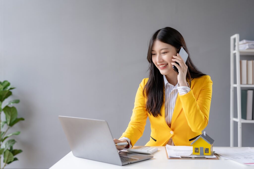 Asian businesswoman talking on the phone professionally in her office. Home sales agent, loan