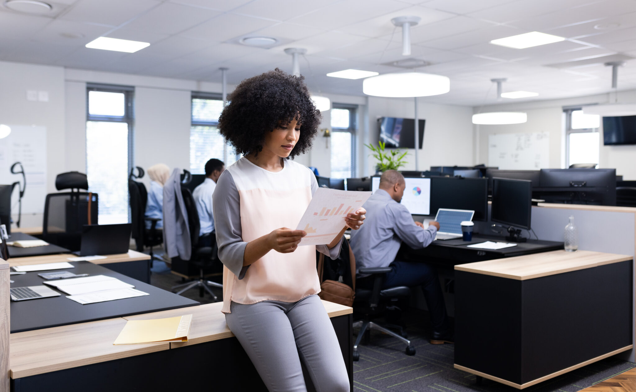 Happy biracial businesswoman with document working in office. Business professionals, job, corporation and working in outsourcing agency